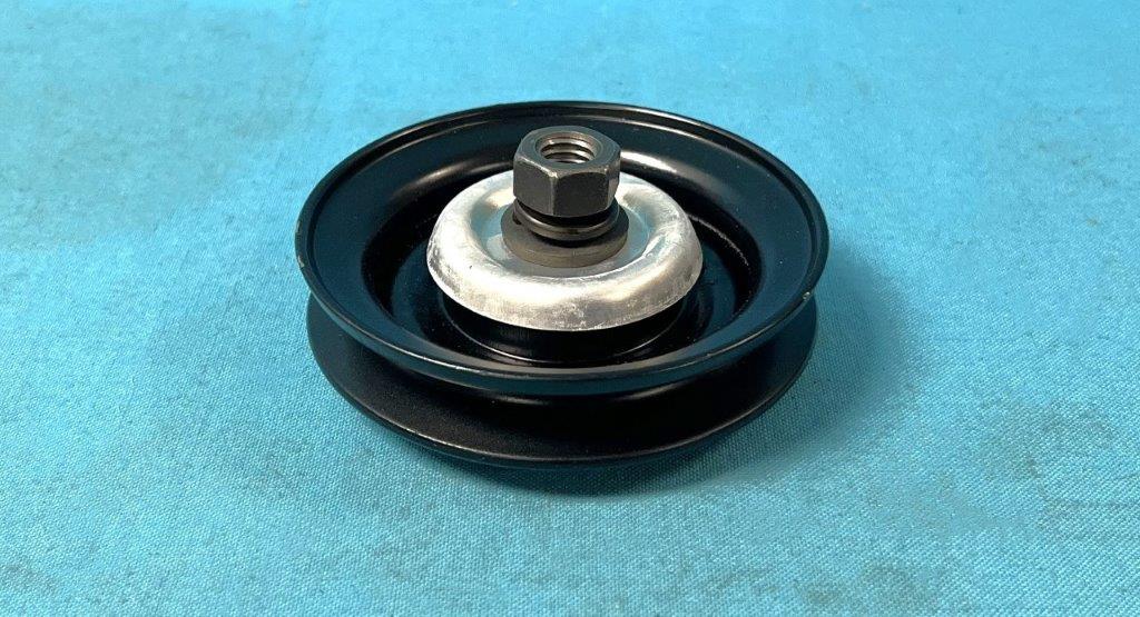 Fan Belt Idler Pulley Assembly for A/C Cars without Leece Neville Alternator.  New pulley and bearing assembly with authentic Formed bearing cover, Grade 8 alloy steel mounting stud, Bearing shield, spacer, lock washer, and nut.  Painted low-gloss Black for original appearance.