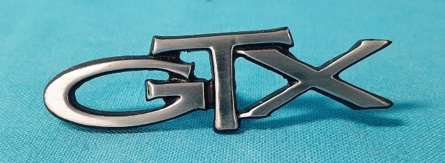 Trunk / Fender nameplate "GTX".  Also used for the rear seat.  See part #PI-81067 GTX if needing the emblem with the backing plate for the rear seat option.  For 1967, 1970-72 GTX Trunk lid, 1972-74 Fender, and 1973-74 Hood.  Original part # 2840 214