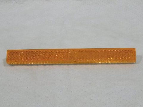 Amber (adhesive) quarter panel reflector lens.
IMPORTANT
Factory side marker reflectors were originally produced by several manufacturers.  Some reflectors had a 1/16" plastic backing underneath the lens while others did not.  This reproduction DOES include the plastic backing, so the lens may extend "outward" further than some originals.  This condition IS NOT AN ERROR.